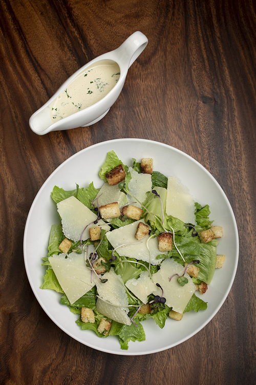 caesar salad with parmesan cheese and croutons on wood table