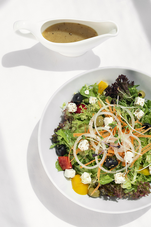 greek salad with feta cheese and olives with citrus vinaigrette on white table