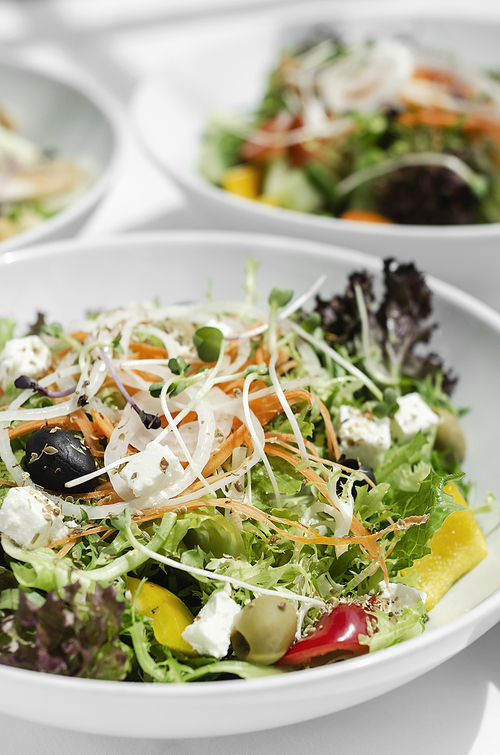 mixed fresh organic salads in bowls on white restaurant table