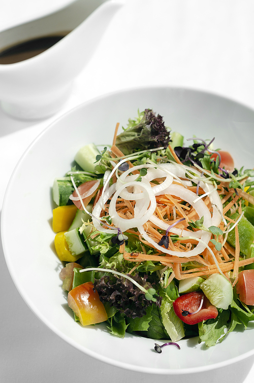 fresh organic mixed vegetable vegan Garden Salad with Vinaigrette sauce on white table