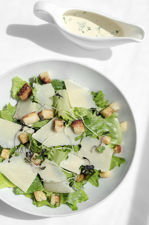 caesar salad with parmesan cheese and croutons on white table