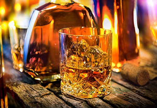 Glass and bottle of whiskey on a wooden table