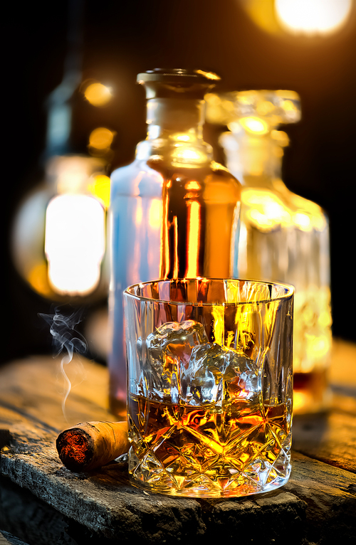 Glass of whiskey and decanter on wooden table