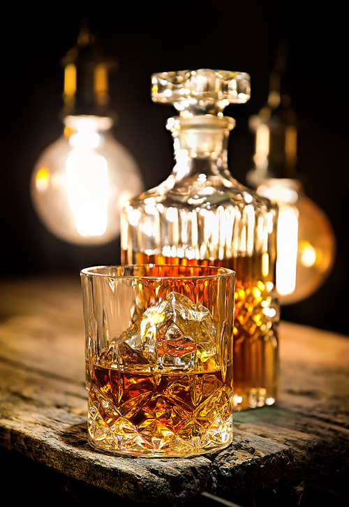 Glass of whiskey and decanter on wooden table