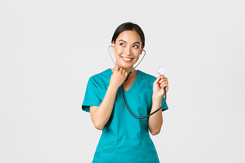 Covid-19, healthcare workers and preventing virus concept. Smiling cute asian doctor, female nurse examine patient lungs, using stethoscope, listening closer, standing white background.