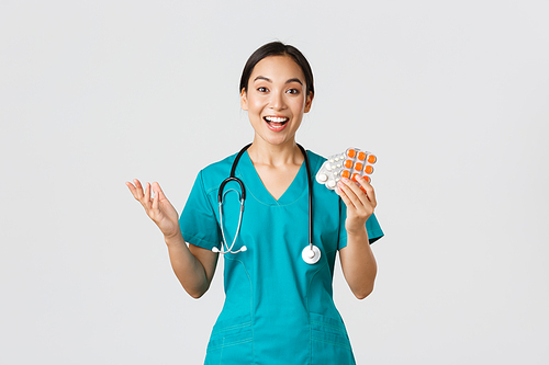 Healthcare workers, preventing virus, quarantine campaign concept. Excited happy asian female physician, nurse in medical mask showing amazing new medication, recommend drugstore.