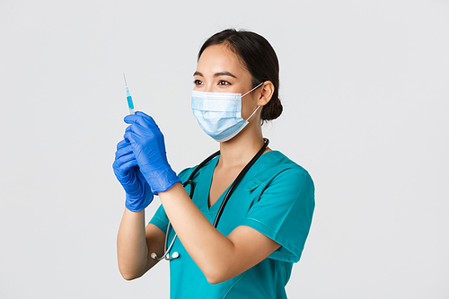 Covid-19, coronavirus disease, healthcare workers concept. Side view of confident smiling asian female physician, nurse prepare syringe with vaccine for flu shot, standing white background.