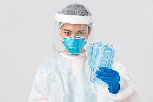 Covid-19, coronavirus disease, healthcare workers concept. Confident serious-looking female asian doctor in personal protective equipment insist patient wearing medical masks, white background.