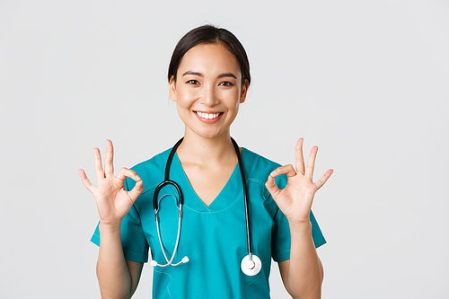 Healthcare workers, preventing virus, quarantine campaign concept. Satisfied good-looking asian female nurse, doctor showing okay gesture in approval, recommend or guarantee perfect service.