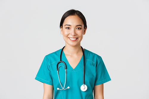 Healthcare workers, preventing virus, quarantine campaign concept. Close-up of smiling pleasant asian female nurse, physician in scrubs looking upbeat, listening to patient, white background.