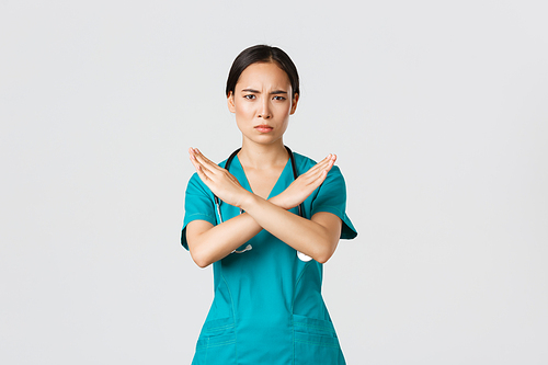 Covid-19, healthcare workers, pandemic concept. Displeased serious-looking concerned asian female doctor show cross gesture, want you stop, prohibit or forbid dangerous action, white background.