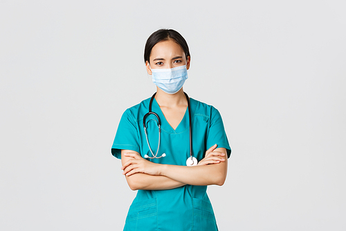 Covid-19, coronavirus disease, healthcare workers concept. Concerned and worried serious-looking asian female doctor inform patient bad results, wear medical mask and scrubs, look disappointed.