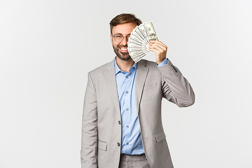 Image of successful businessman in grey suit and glasses, showing money and smiling, concept of investment and finance.