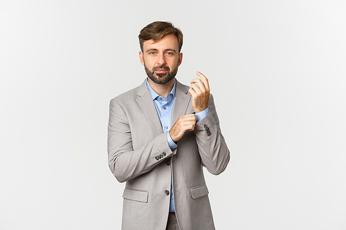 Image of handsome adult businessman with beard, getting dressed in suit, looking confident, standing over white background.