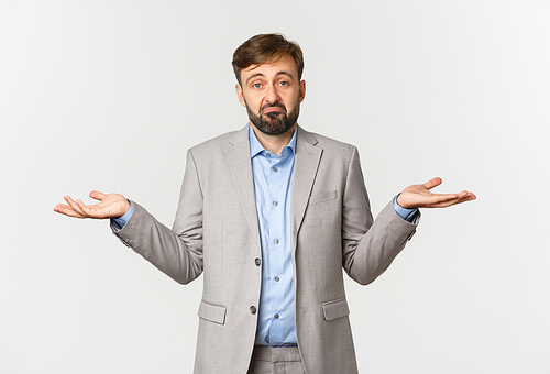 Portrait of sad businessman in grey suit, shrugging and looking puzzled, dont know anything, standing confused over white background.