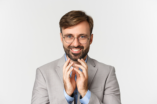 Close-up of bearded businessman in glasses and suit, scheming something, smiling devious and having perfect plan, standing over white background.