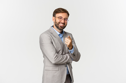 Portrait of satisfied male employer in glasses and grey business suit, pointing at you and praising good job, smiling pleased, standing over white background.