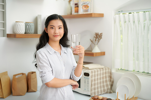 Young woman drinking water from glass in the kitchen