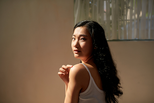 Young skin care woman applying body lotion on arm and shoulder at home