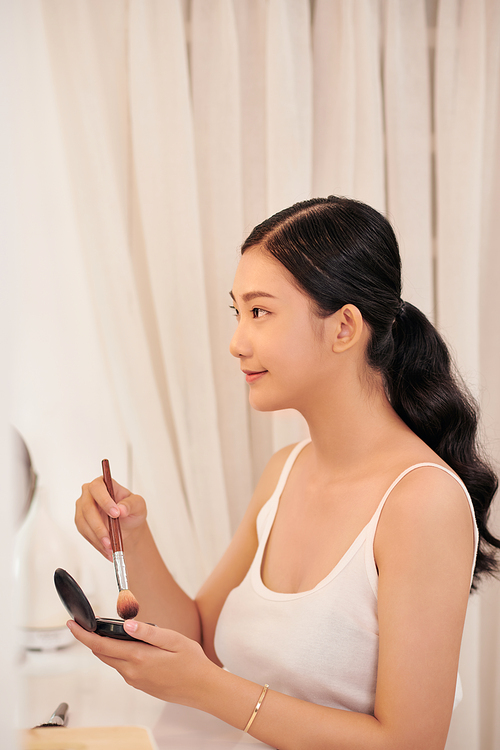 Beauty model girl applying makeup and smiling