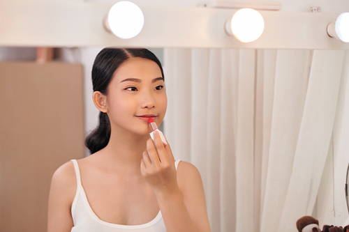 woman applying make up for a evening date in front of a mirror. Focus on her reflection