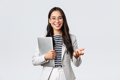 Business, finance and employment, female successful entrepreneurs concept. Smiling professional businesswoman, real estate broker showing clients good deal, carry laptop in hand.