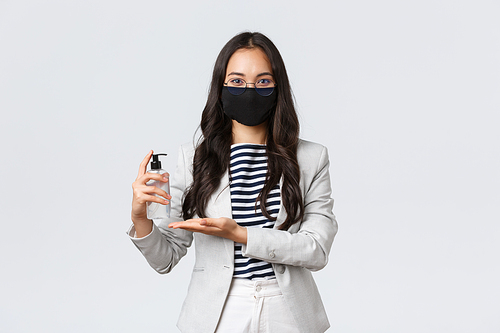 Business, finance and employment, covid-19 preventing virus and social distancing concept. Asian female entrepreneur face mask apply hand sanitizer to wash hands while at office working with people.