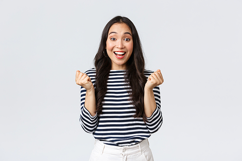 Lifestyle, people emotions and casual concept. Cheerful happy woman rejoicing from good news, fist pump and looking surprised as winning, achieve goal and celebrating victory.