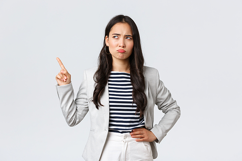 Business, finance and employment, female successful entrepreneurs concept. Skeptical and hesitant office manager, asian businesswoman in suit having doubts, smirk and pointing upper left corner.