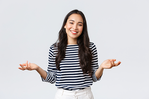 Lifestyle, beauty and fashion, people emotions concept. Smiling cute clueless girl dont have idea, no answer, shrugging with hands spread sideways, standing white background.