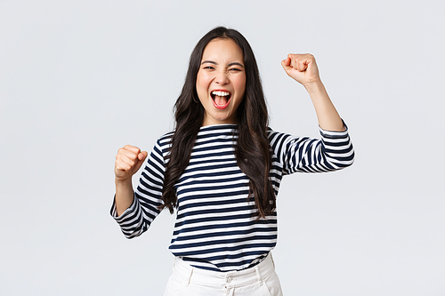 Lifestyle, people emotions and casual concept. Excited happy asian woman attend sport competition, rooting and chanting for team, raising hands up and shout yes supportive.