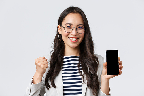Business, finance and employment, female successful entrepreneurs concept. Happy rejoicing businesswoman showing pleasant news on smartphone and fist pump in celebration of victory.