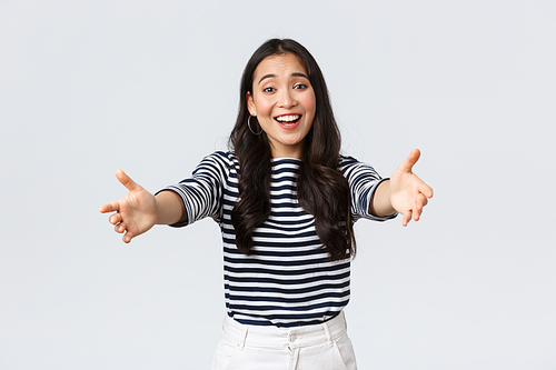 Lifestyle, people emotions and casual concept. Friendly charming asian girl reaching hands forward to hold something, giving hug or embracing, standing white background.