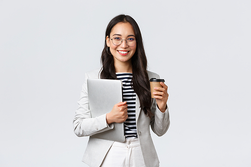 Business, finance and employment, female successful entrepreneurs concept. Confident good-looking businesswoman in glasses and suit drinking takeaway coffee and carry work laptop.