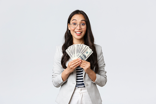 Business, finance and employment, entrepreneur and money concept. Successful young asian office manager, businesswoman showing earned cash, smiling satisfied as holding dollars.