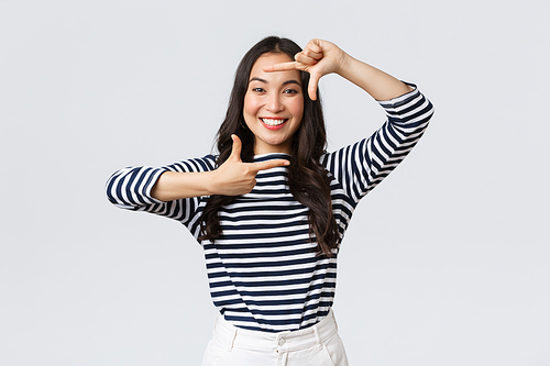 Lifestyle, people emotions and casual concept. Creative cute asian girl picturing, capture moment with hand frames gesture, smiling amused, staying positive and happy, white background.