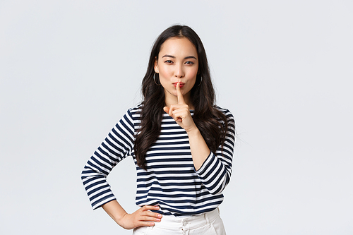 Lifestyle, people emotions and casual concept. Smiling cute asian girl asking keep secret, take promise not tell or be quiet about it, show shush sign, hush with finger over mouth, prepare surprise.