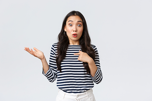 Lifestyle, beauty and fashion, people emotions concept. Shocked and surprised girl pointing at herself and shrugging as was picked or chosen, standing white background.