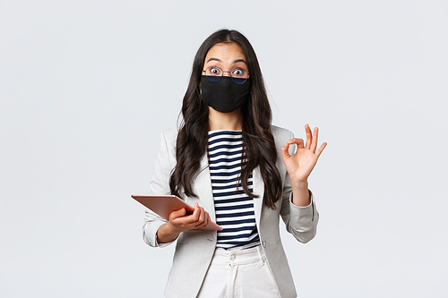 Business, finance and employment, covid-19 preventing virus and social distancing concept. Asian businesswoman with digital tablet, wear protective mask against virus and showing okay sign.