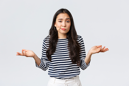 Lifestyle, beauty and fashion, people emotions concept. Smiling cute clueless girl dont have idea, no answer, shrugging with hands spread sideways, standing white background.