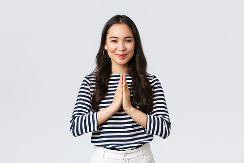 Lifestyle, people emotions and casual concept. Cute asian girl in casual outfit smiling as saying namaste, holding hands in pray, pleading or greeting guests with polite bow.