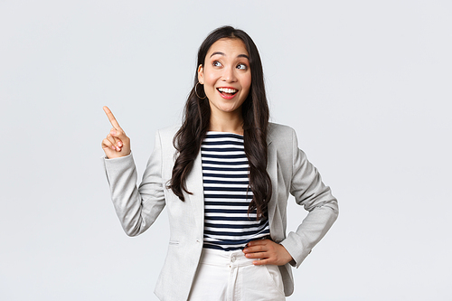 Business, finance and employment, female successful entrepreneurs concept. Cheerful successful businesswoman in white suit pointing fingers upper left corner, showing advertisement.