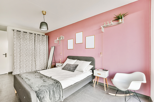 Stunning bedroom with a pink wall and paintings on it and an unusual chandelier