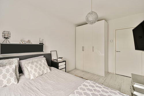The interior of a bedroom with a gray and white design and a large wardrobe in a cozy apartment