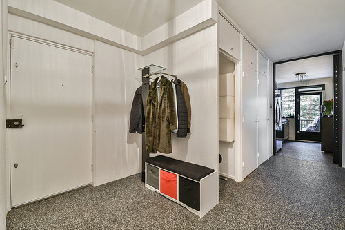 A spacious corridor with carpeted floors and a clothes rack at the entrance to the house