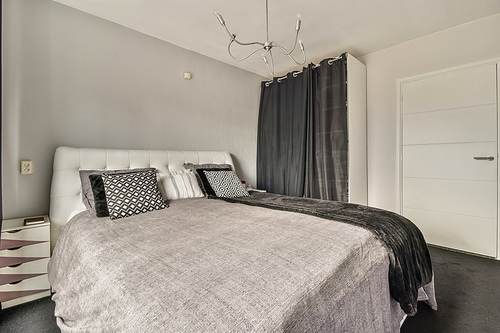 The interior of a bedroom with a black and gray design and a large wardrobe in a cozy apartment