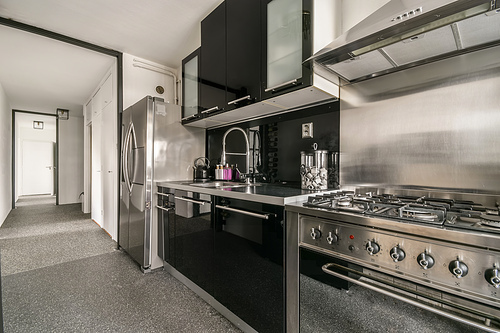 Kitchen in dark colors with modern appliances and carpet on the floor in a cozy house