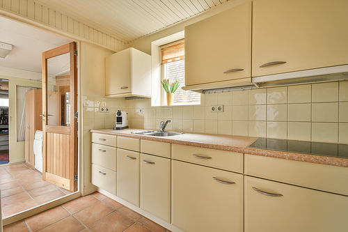 The interior of the kitchen with light furniture on the tiled floor in a cozy house