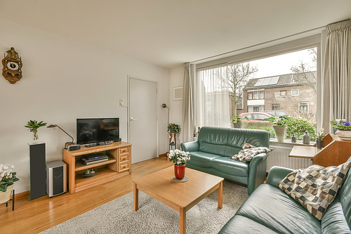 The interior of the living room with two sofas in front of the TV near to the big window in a cozy house