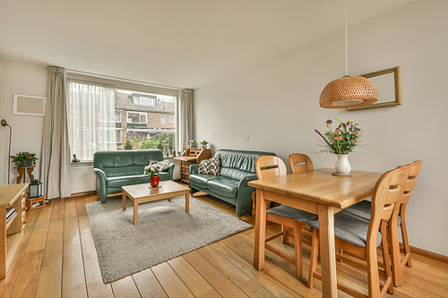 The interior of the living room with two sofas near to the big window and a dining area in a cozy house